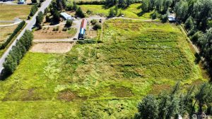 Aerial view of rural acreage in Whatcom County with a home, outbuildings, and open pasture